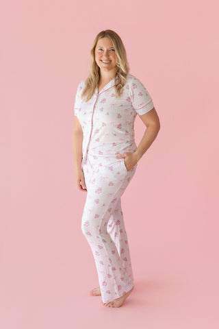 White pajama set with pink rose and ribbon print, short-sleeved button-up top and flare pants.