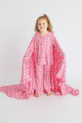 Child wrapped in pink ruffle blanket with ribbon and bow pattern print.