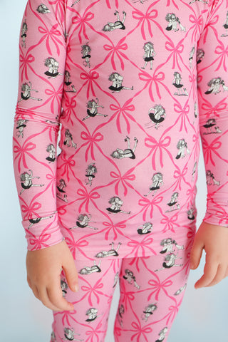 Pink pajamas with bright pink bows and illustrated girls in black dresses throughout the pattern.