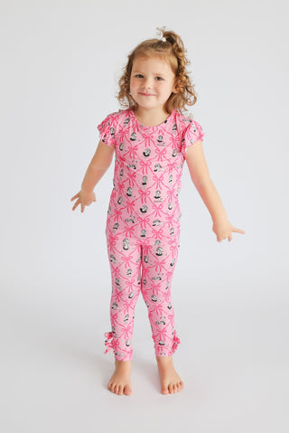 Young child wearing pink short-sleeve pajama set with ribbon bow and dancer print throughout, featuring ruched ankle cuffs.