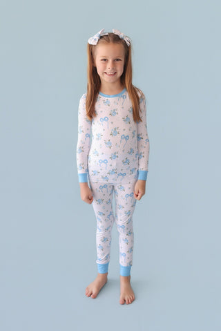Pair of powder blue bow hair clips worn by child on brown hair against blue background.