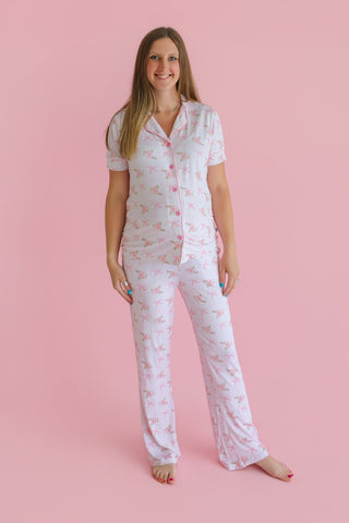 Woman wearing white short-sleeve pajama set with pink floral print and flare pants.