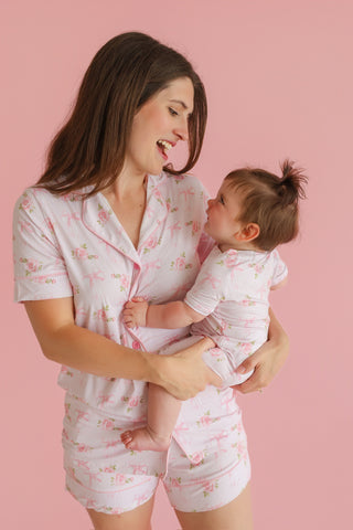 Woman and toddler wearing matching white short sets with pink floral and bow prints.