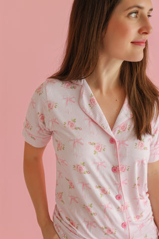 White ribbed short-sleeve top with pink floral and bow pattern, button front closure.