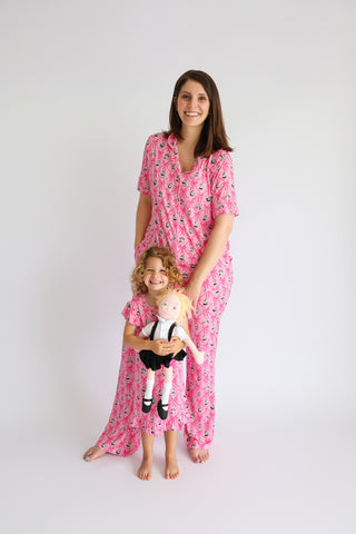 Woman and child wearing matching pink flare pajama sets with ribbon print pattern.