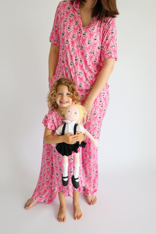 Woman and child wearing matching pink pajama sets with ribbon and anchor print pattern.