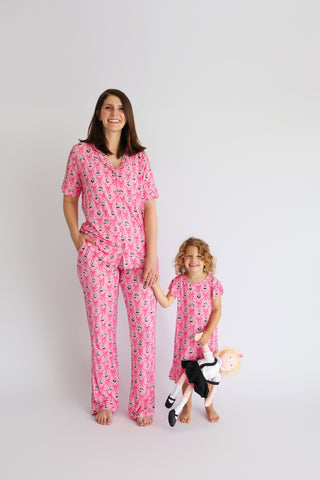 Woman and child wearing matching pink pajama sets with sailboat and crown print pattern.