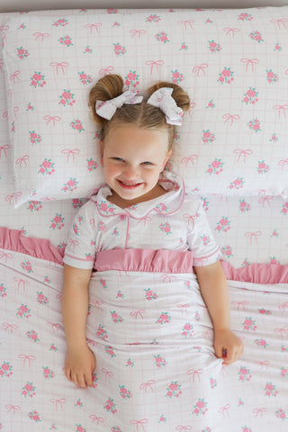 Two white bow hair clips with pink floral print secured on child's hair buns.