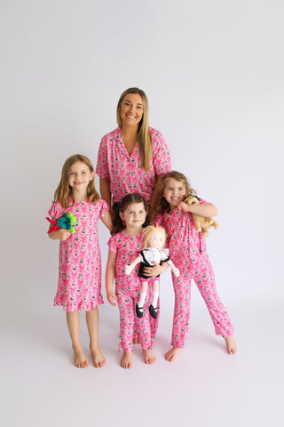 Adult and children wearing pink pajamas with crown and ribbon print pattern.