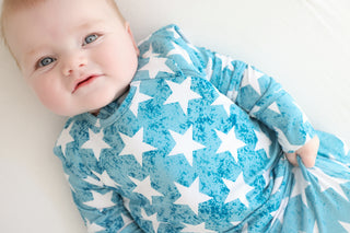 Infant in blue sleep sack with white stars and textured pattern.
