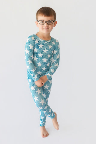 Child wearing teal two-piece pajamas with white star print throughout.