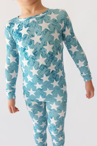 Child wearing teal long-sleeve top and matching pants with white star print throughout.