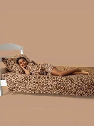 Twin sheet set with tan and black leopard print pattern on bed with white headboard.