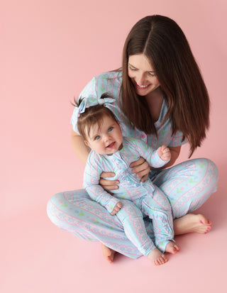 Woman and toddler wearing matching blue pajama sets with colorful tulip print and flare pants.