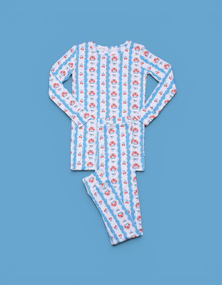 Two-piece children's pajama set with red floral and blue bow pattern on white background.
