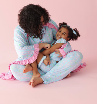 Woman and child wearing matching blue striped pajama sets with pink ruffled trim on sleeves and pant legs.