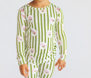 Child wearing green and white striped pajama set with pink floral print throughout.