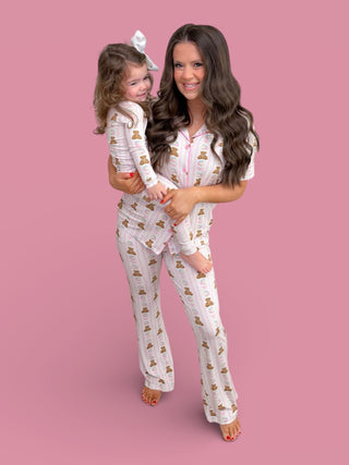 Adult and child wearing matching white pajama sets with bear and floral print, styled against pink background.