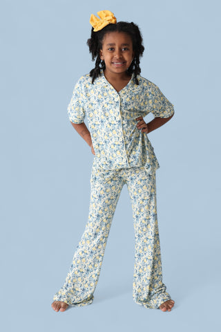Girl's two-piece pajama set with yellow and blue citrus toile print, short-sleeve button-up top and flared pants.