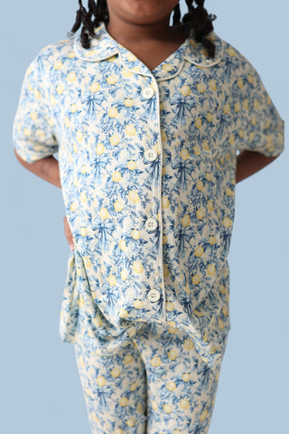 Girl's two-piece set with blue and yellow floral toile print, short-sleeve button-up shirt and matching flare pants.