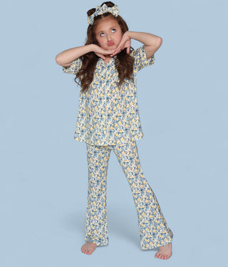 Girl wearing citrus toile print short-sleeve shirt and matching flare pants with headband.