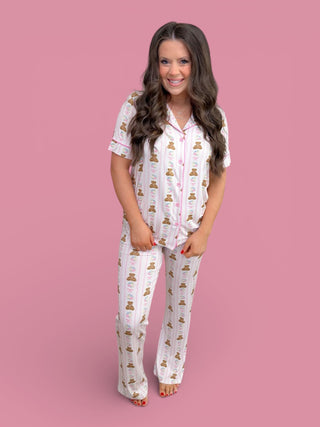 White short-sleeve pajama set with teddy bear and floral print, button-up shirt with flare pants.