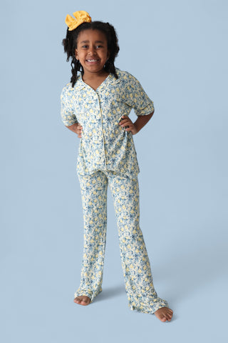 Girl's two-piece pajama set with yellow and blue citrus toile print, short-sleeve button-up shirt and flared pants.