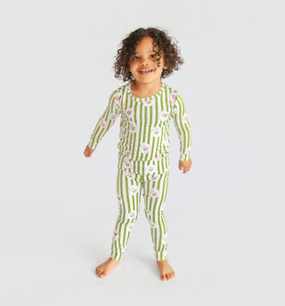 Young child wearing green and white striped pajama set with pink floral pattern, long sleeves and pants.