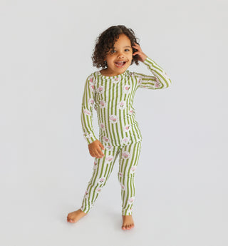 Toddler wearing green and white striped pajamas with pink floral pattern, long sleeves and full-length pants.
