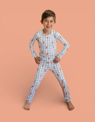 Child wearing blue and white checkered pajama set with carrot print throughout.