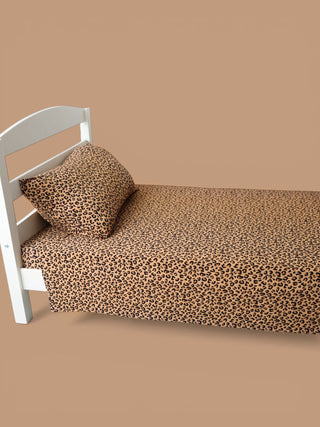 Twin sheet set with leopard print pattern in tan and black on a white bed frame.