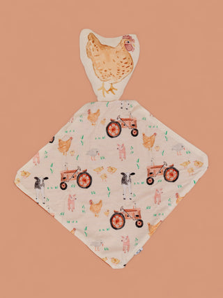 Cream plush lovey with chicken head and patterned body featuring farmyard animals, tractors, and grass on tan background.