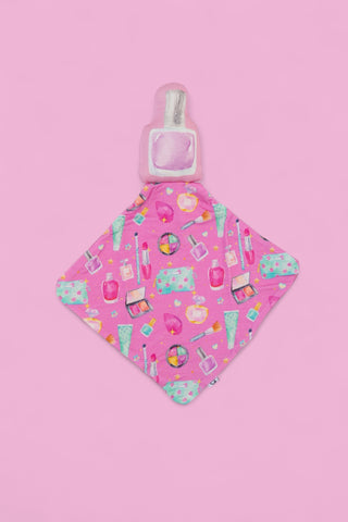 Pink plush lovey with perfume bottle head and diamond-shaped fabric printed with makeup and beauty product designs.