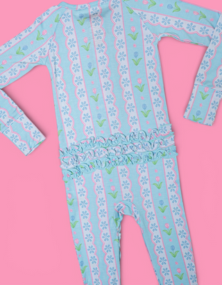 Light blue romper with white daisy and pink tulip print, ruffled waistband, and long sleeves.