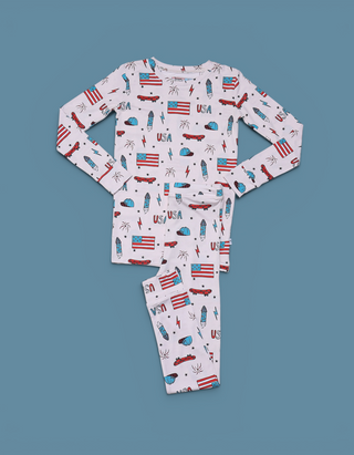 Light pink pajama set with long sleeves and pants featuring red skateboards, blue flags, "USA" text, and stars on blue backgr