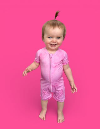 Toddler wearing a pink short-sleeve zip-up romper with striped trim on sleeves against a bright pink background.