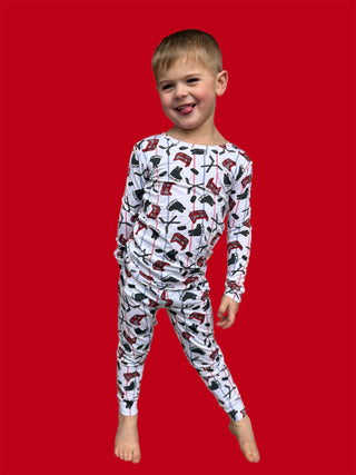 Young child wearing white long-sleeved pajamas with red and black hockey and skating print pattern.