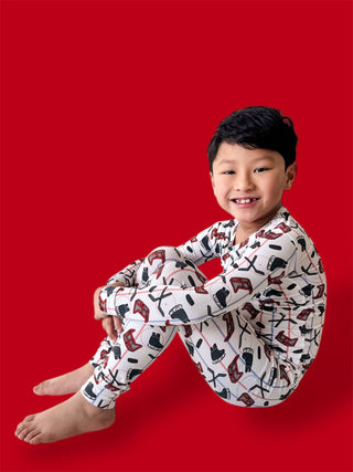 Child wearing cream pajamas with hockey sticks and skates pattern against red background.