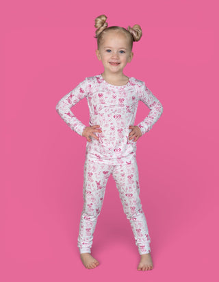 Toddler wearing white long-sleeve pajama set with pink puppy and floral toile pattern.