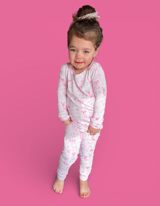 Toddler wearing white long-sleeve top and cropped pants with pink puppy print pattern.