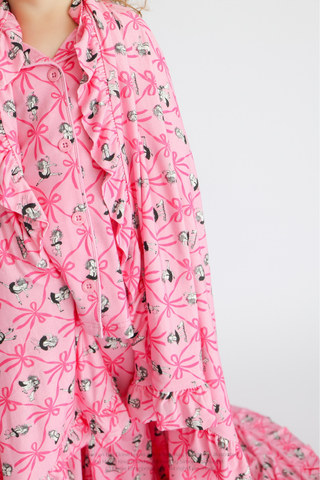 Pink blanket with ribbon bows and illustrated figures, featuring ruffled edges and button closures.