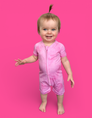 Toddler wearing pink short-sleeve romper with striped trim and front zipper against bright pink background.